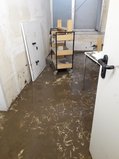 Der ursprünglich weiße Kellerboden ist bedeckt mit braunem, feuchtem Schlamm.